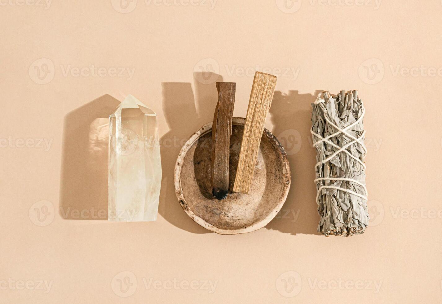 Collection items for spiritual cleansing - sage bundle, palo santo incense sticks and quartz crystal on beige background. photo