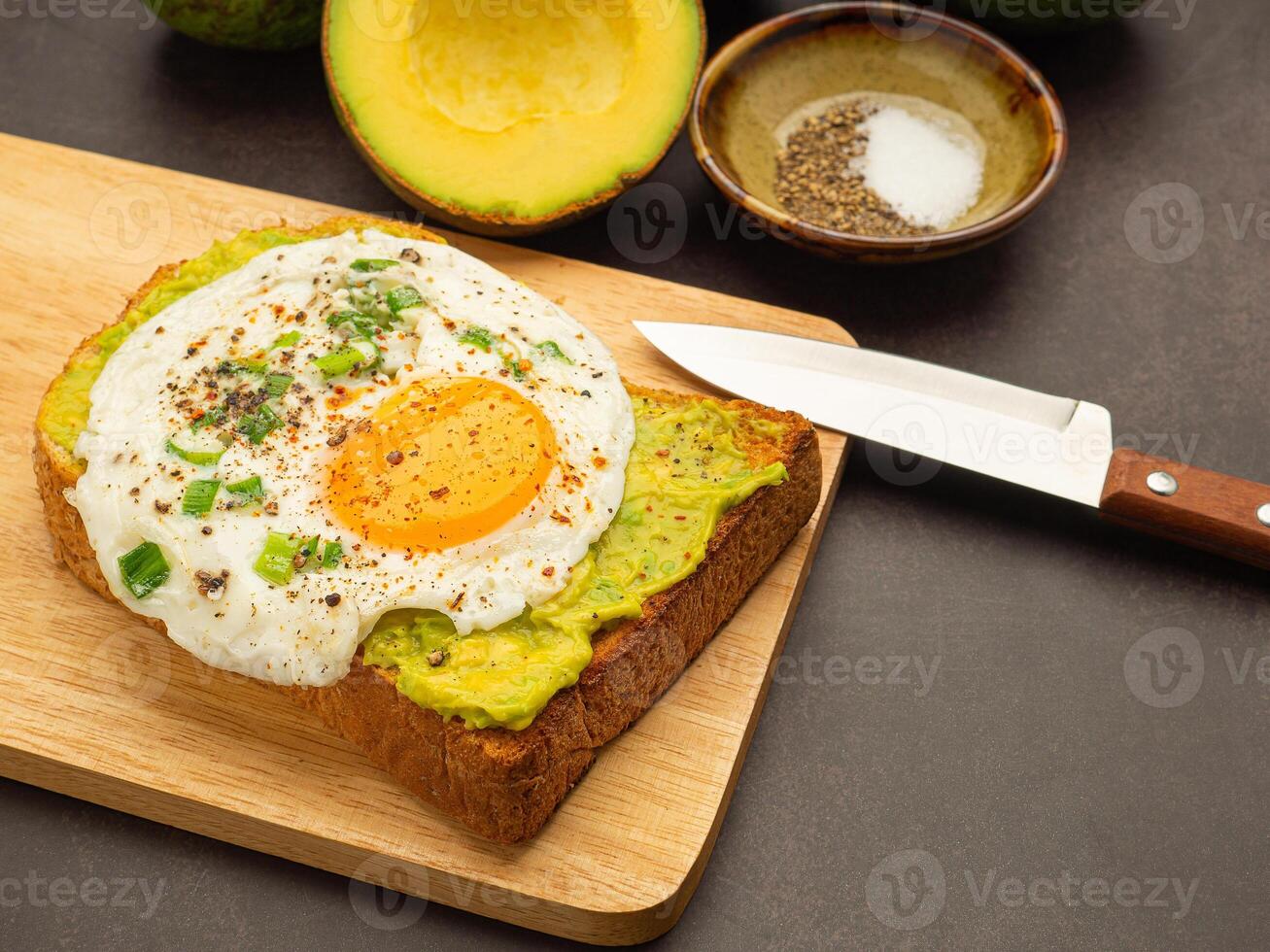 Toast with avocado and eggs served on a wooden cutting board. Top view. Space for text photo