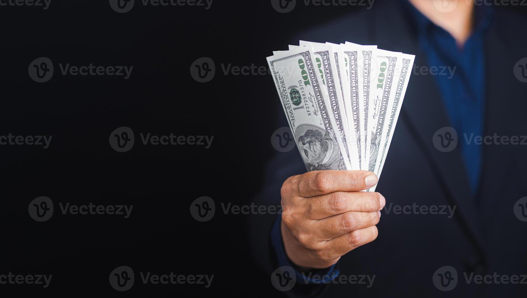 Hand holding of a US dollars banknote with a black background while standing in the studio. Close-up photo. Space for text photo