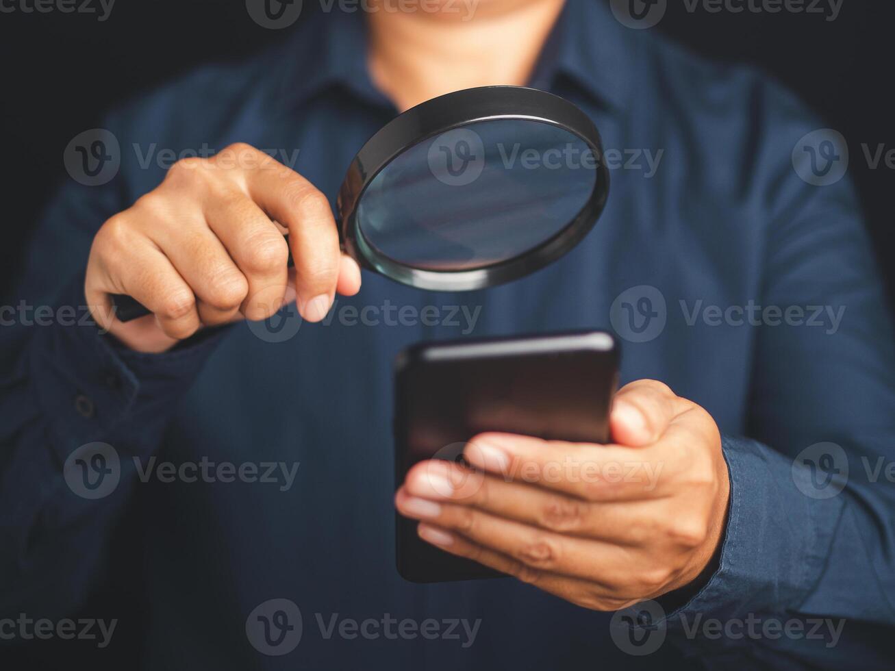 Businessman using a smartphone with a magnifying glass. Close-up photo. Search online concept photo