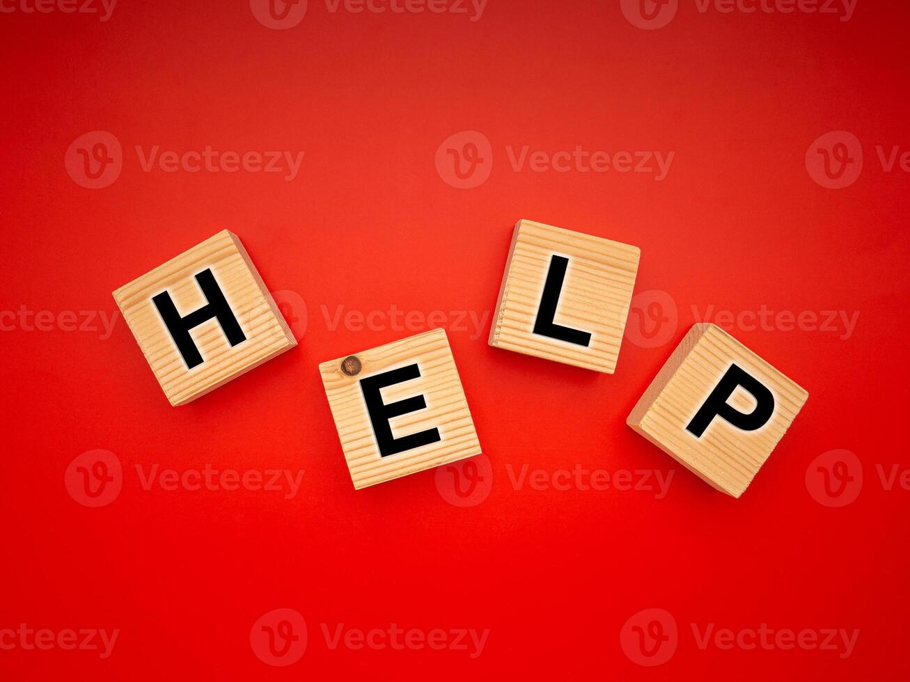 HELP word is written on wood blocks isolated on a red background. Top view. Close-up photo