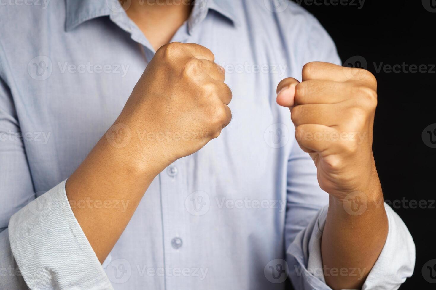 Hand of businessman raised fist air with a black background. Space for text. Concept of victory, success, and winning photo