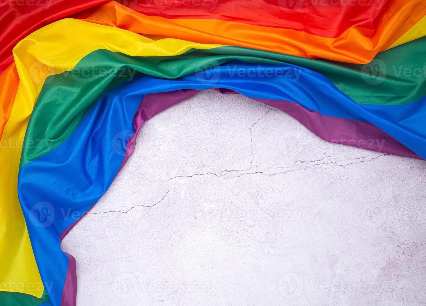 The rainbow flag is on a cement floor with space for text. photo