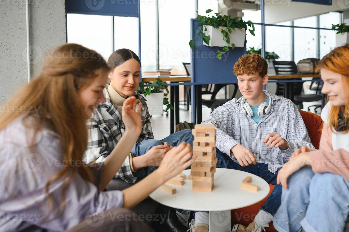 group of young friends playing board games together while sitting around table photo