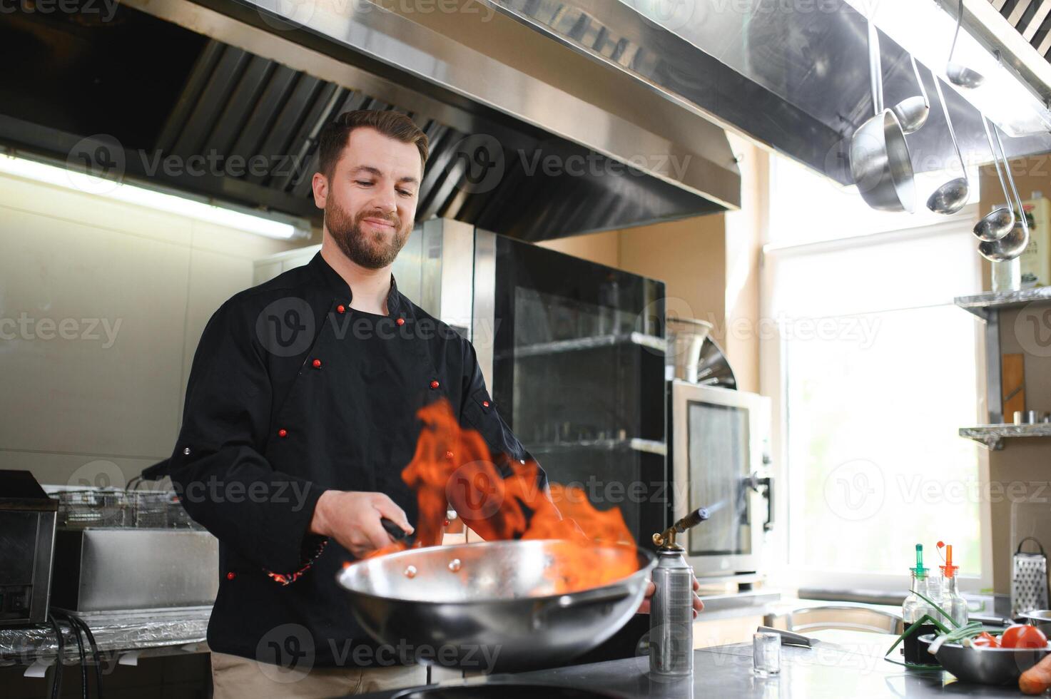 Chef cooking and doing flambe on food in restaurant kitchen photo