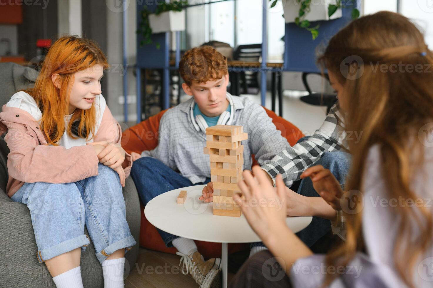 The company of young people plays a table game called jenga photo