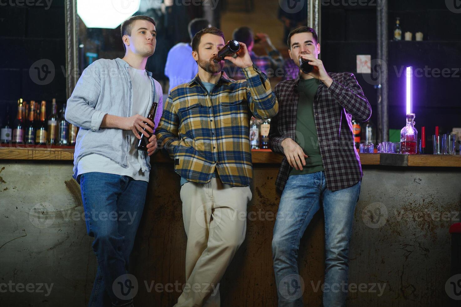Friends having fun. Happy young men in casual wear drinking beer in pub. photo