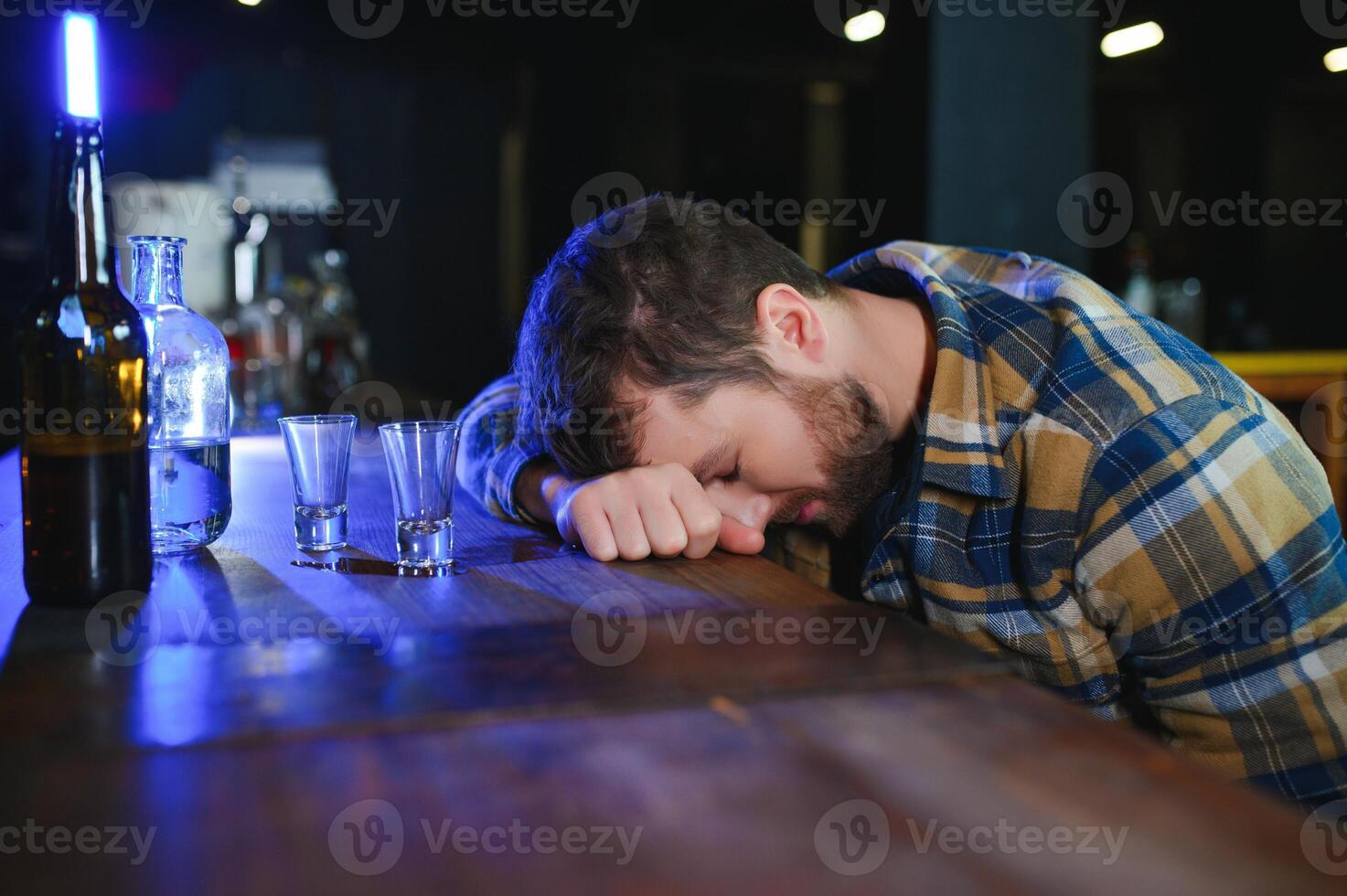 Drunk man sleeps at bar counter, alcohol addiction photo