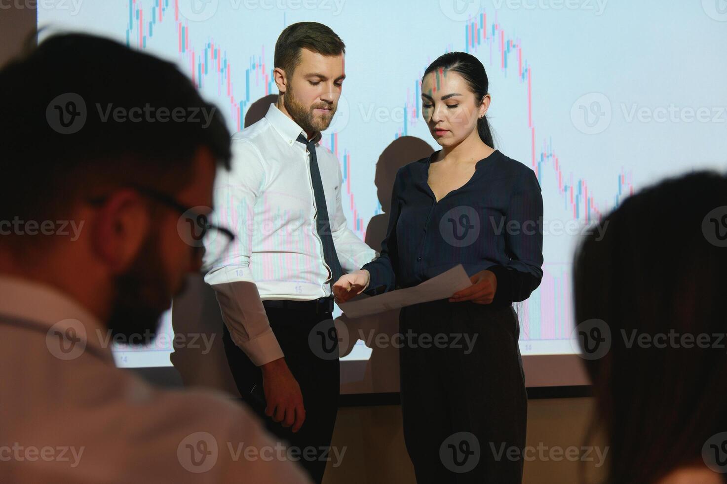 Trading teaching. Male leader talking to employees, showing the plan on the projector in office of stock exchange company. photo