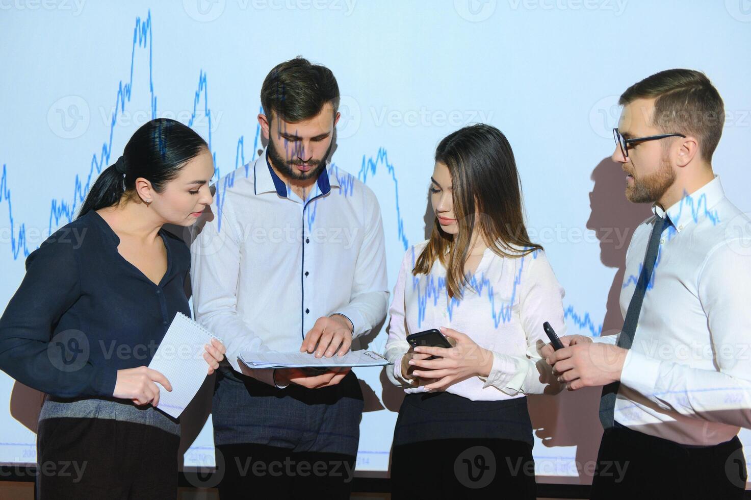 Business Conference Meeting Presentation Businessman does Financial Analysis talks to Group of Businessspeople. Projector Screen Shows Stock Market Data, Investment Strategy, Revenue Growth photo