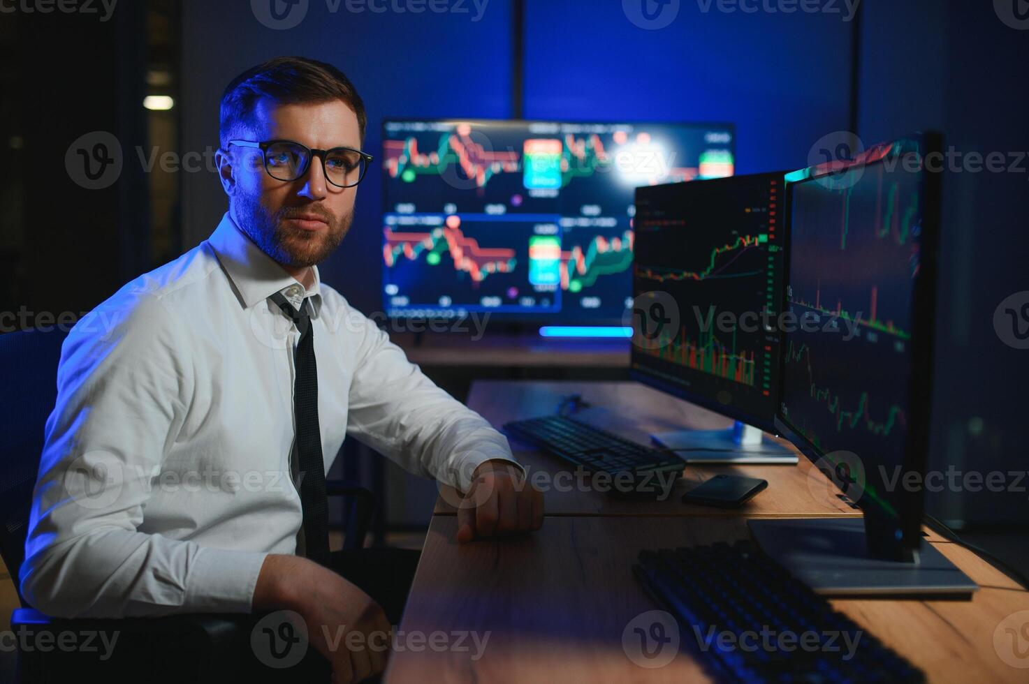 Side view of crypto broker sitting at office table, analyzing market, looking at screen photo