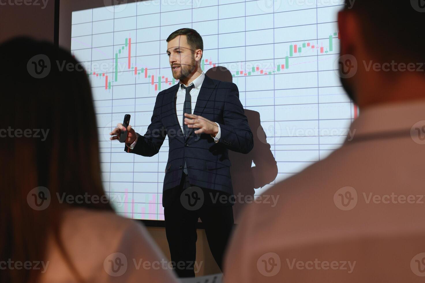 Man is standing near projector and showing graphs and business graphs. photo