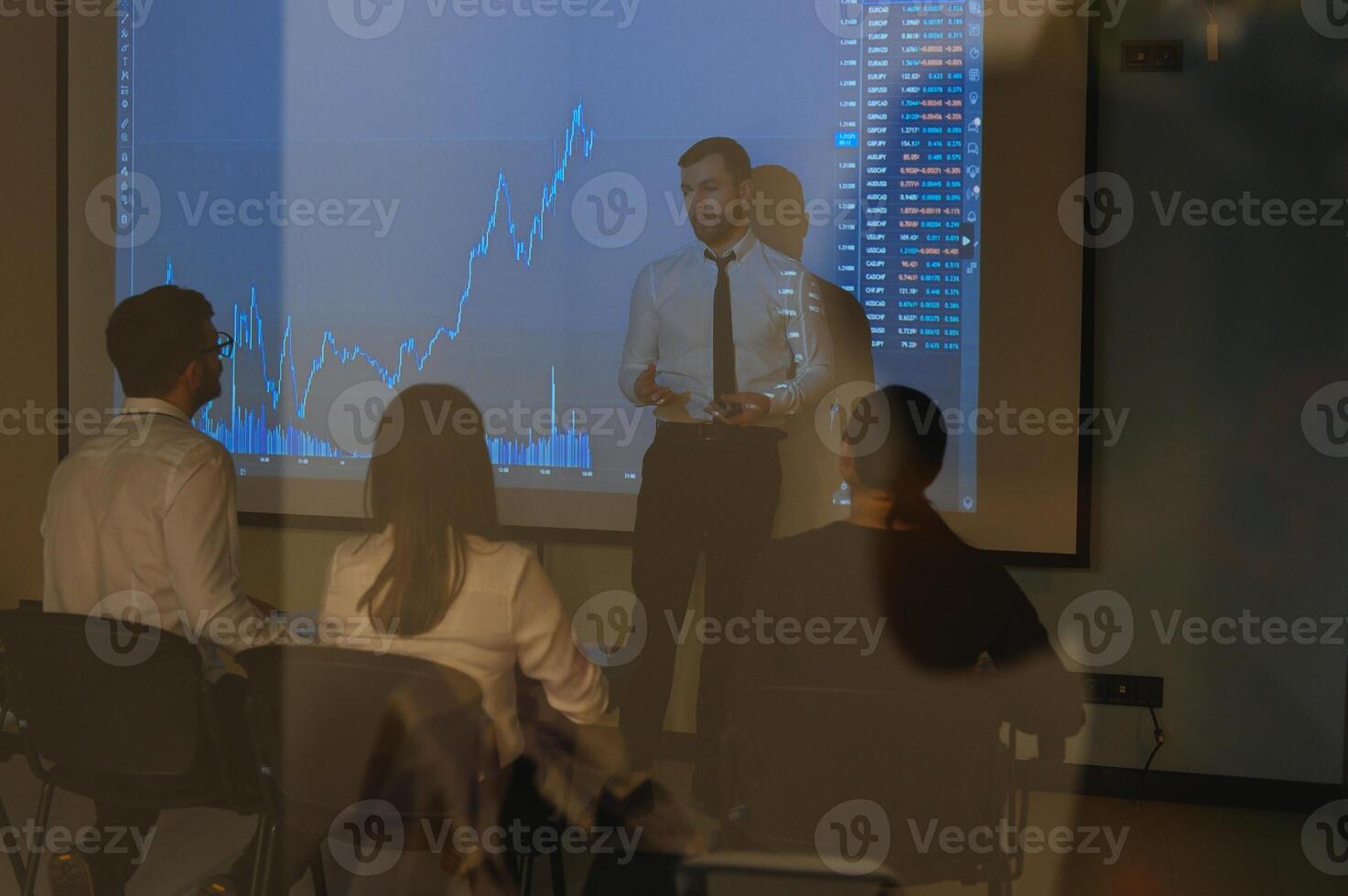 Man is standing near projector and showing graphs and business graphs. photo