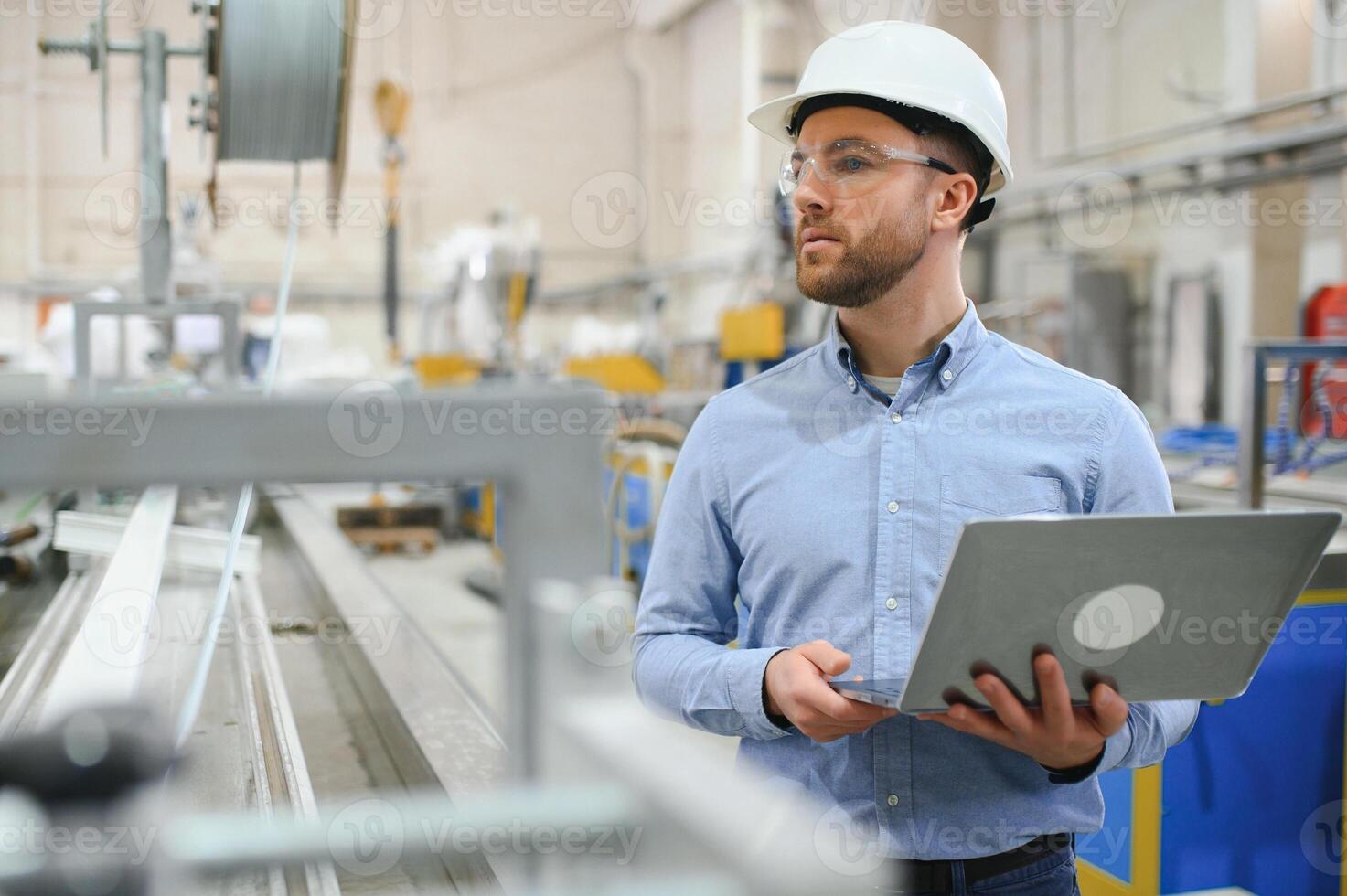 Side view of technician or engineer with headset and laptop standing in industrial factory photo