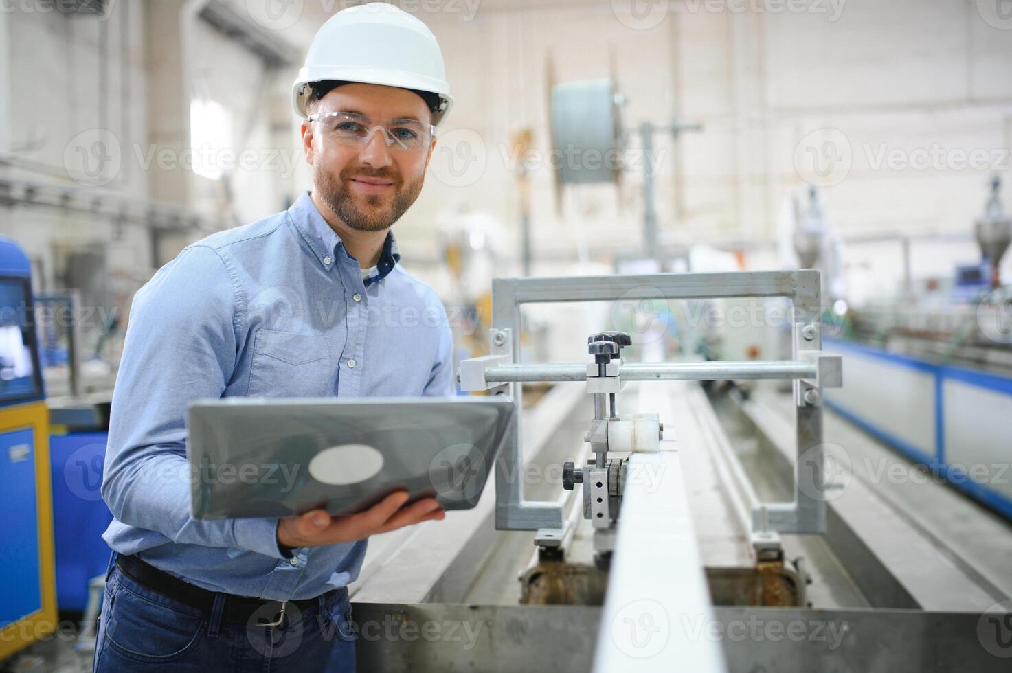 Side view of technician or engineer with headset and laptop standing in industrial factory photo