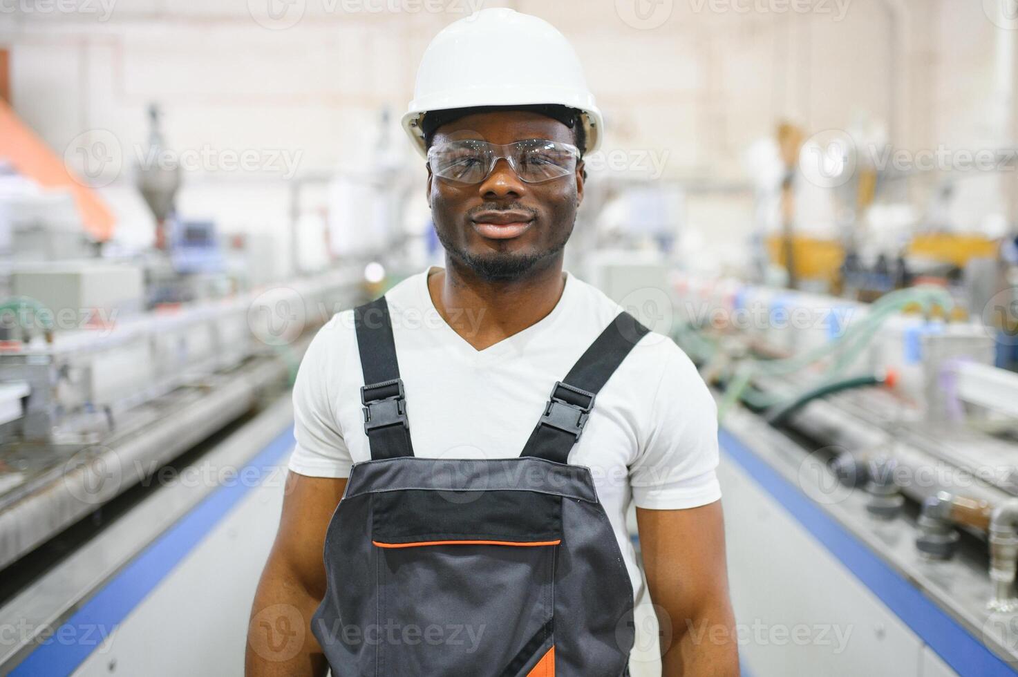 Portrait of industrial engineer. Smiling factory worker with hard hat standing in factory production line photo