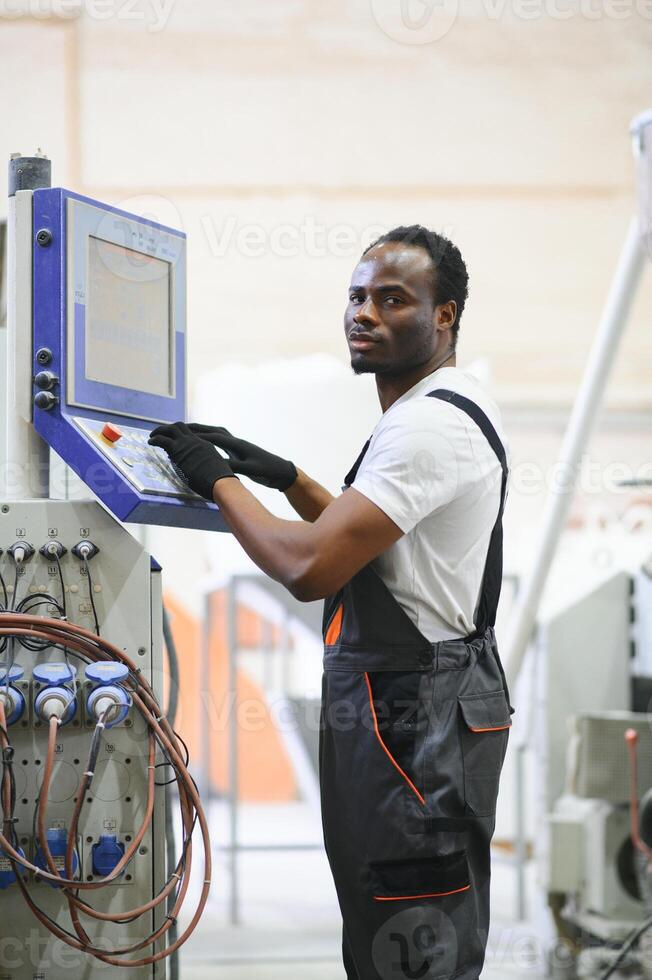 Portrait of African American male engineer in uniform and standing in industrial factory photo