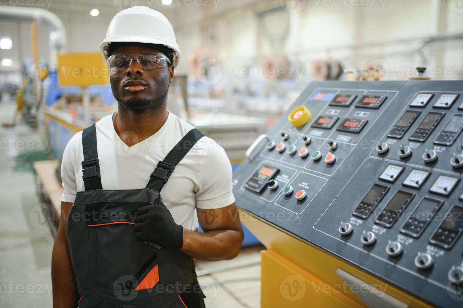 Portrait of African American male engineer in uniform and standing in industrial factory photo