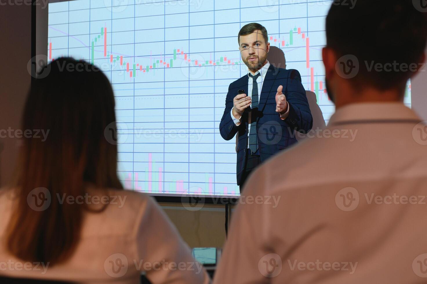 Man is standing near projector and showing graphs and business graphs. photo