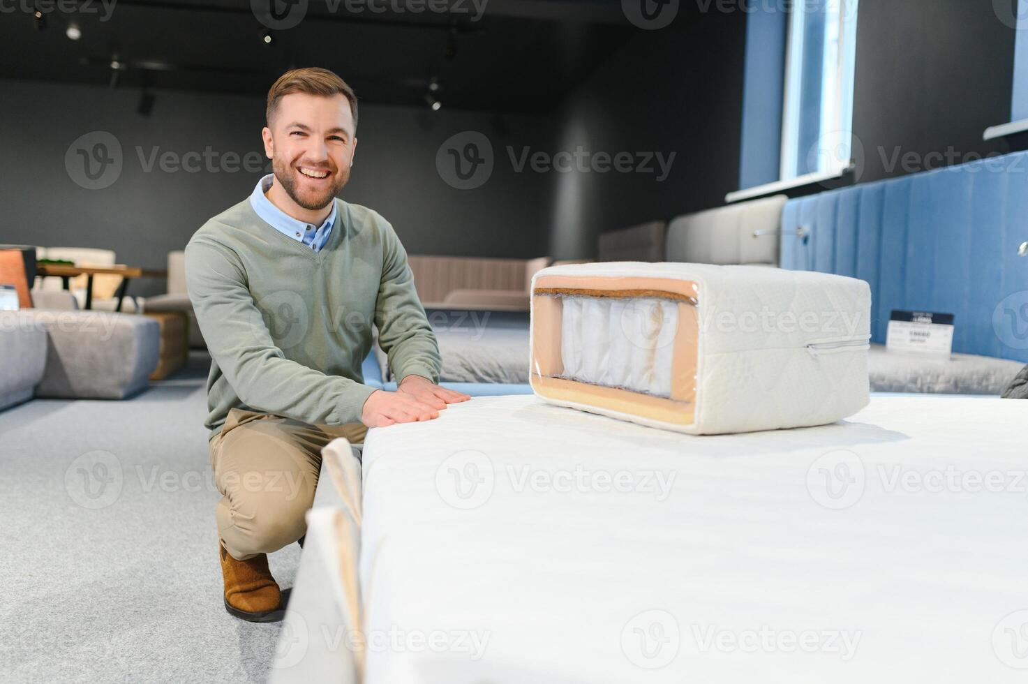 Handsome man examining sample of orthopedic mattress on sale photo