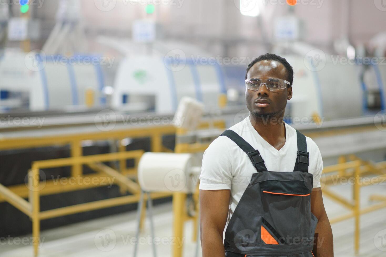 Portrait of African American male engineer in uniform and standing in industrial factory photo