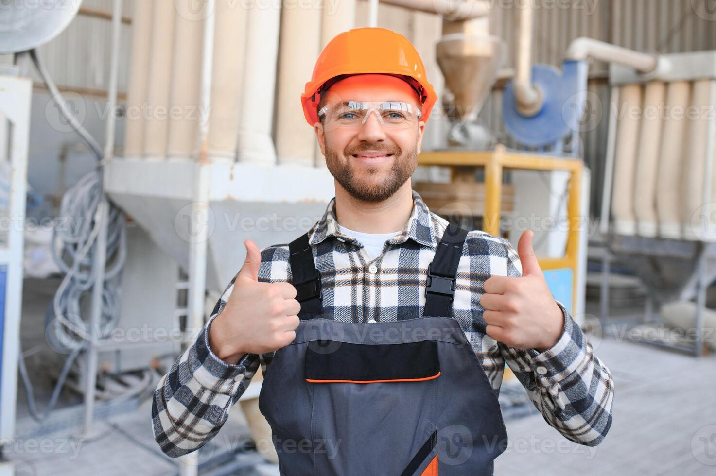 Smiling and happy employee. Industrial worker indoors in factory. Young technician with hard hat photo