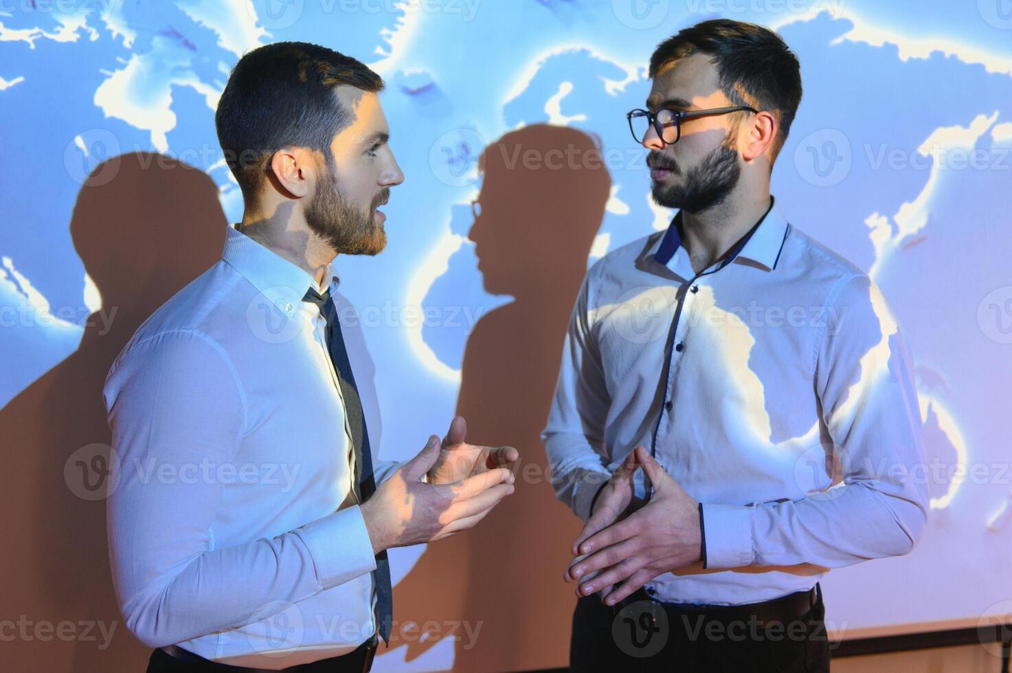 Two Business Colleagues Have Informal Meeting On Stairs Of Office With World Map In Background photo