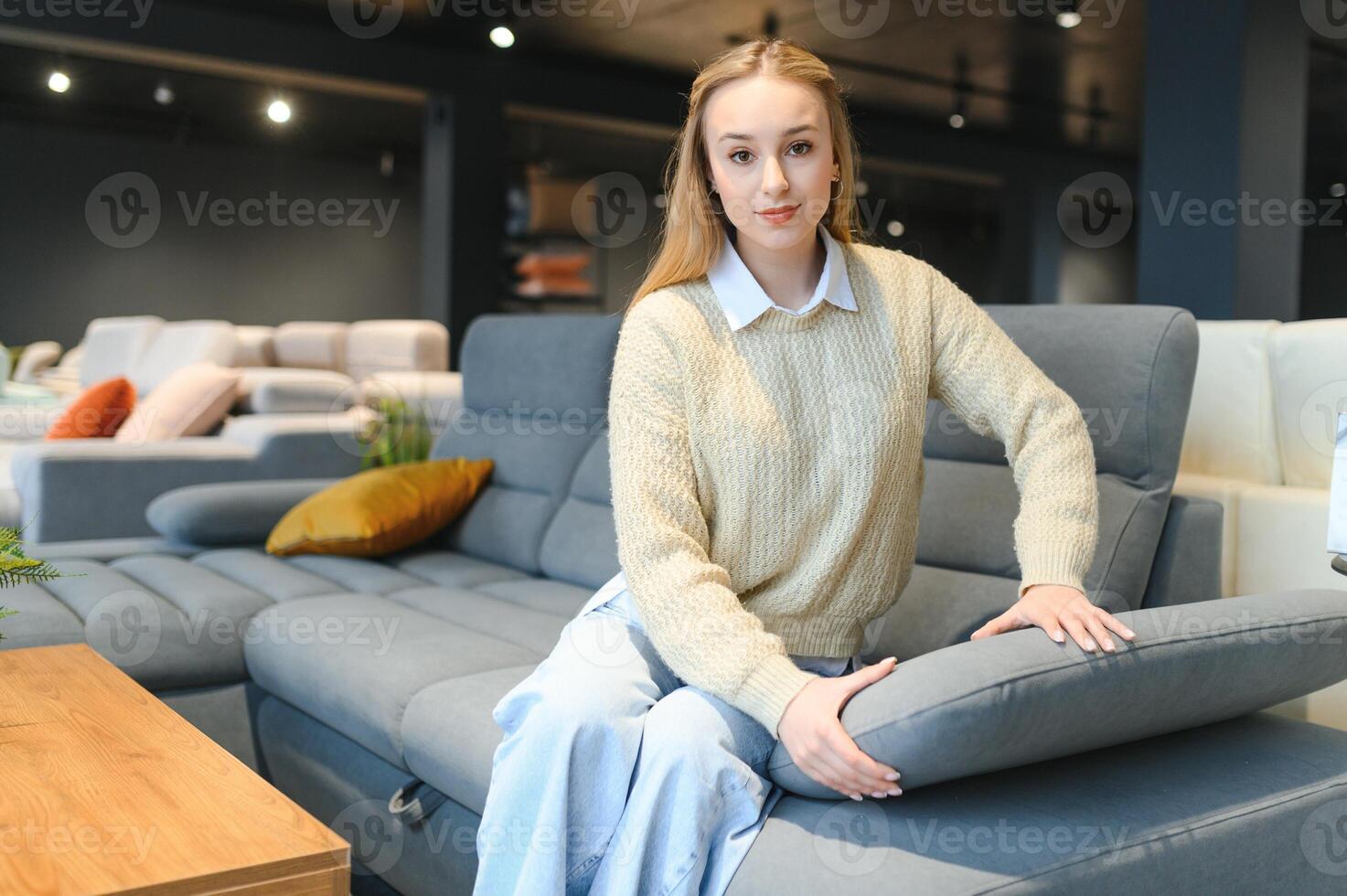 Happy young woman chooses sofa for home in furniture store photo