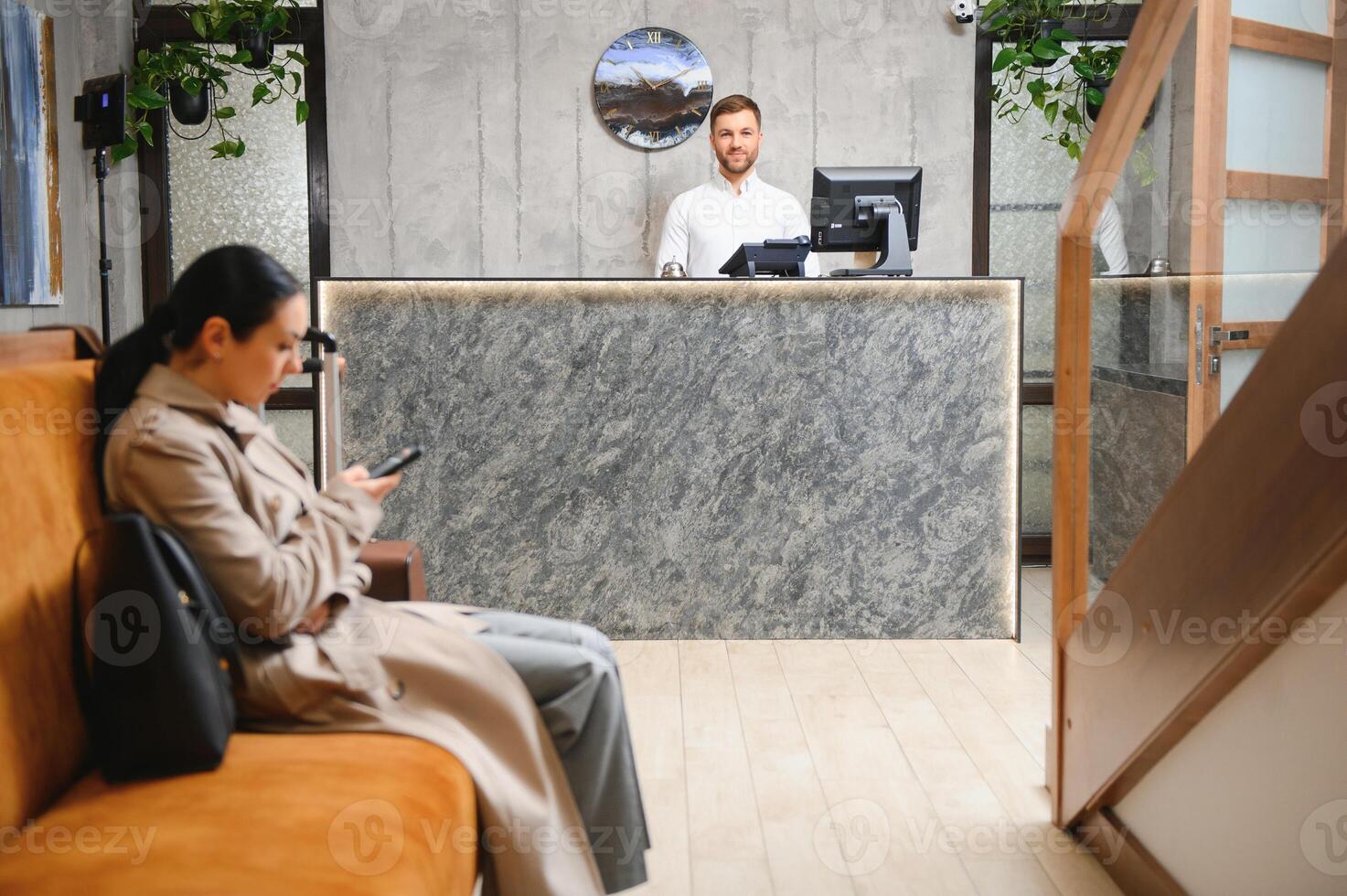 Businesswoman with luggage in modern hotel lobby using smartphone photo
