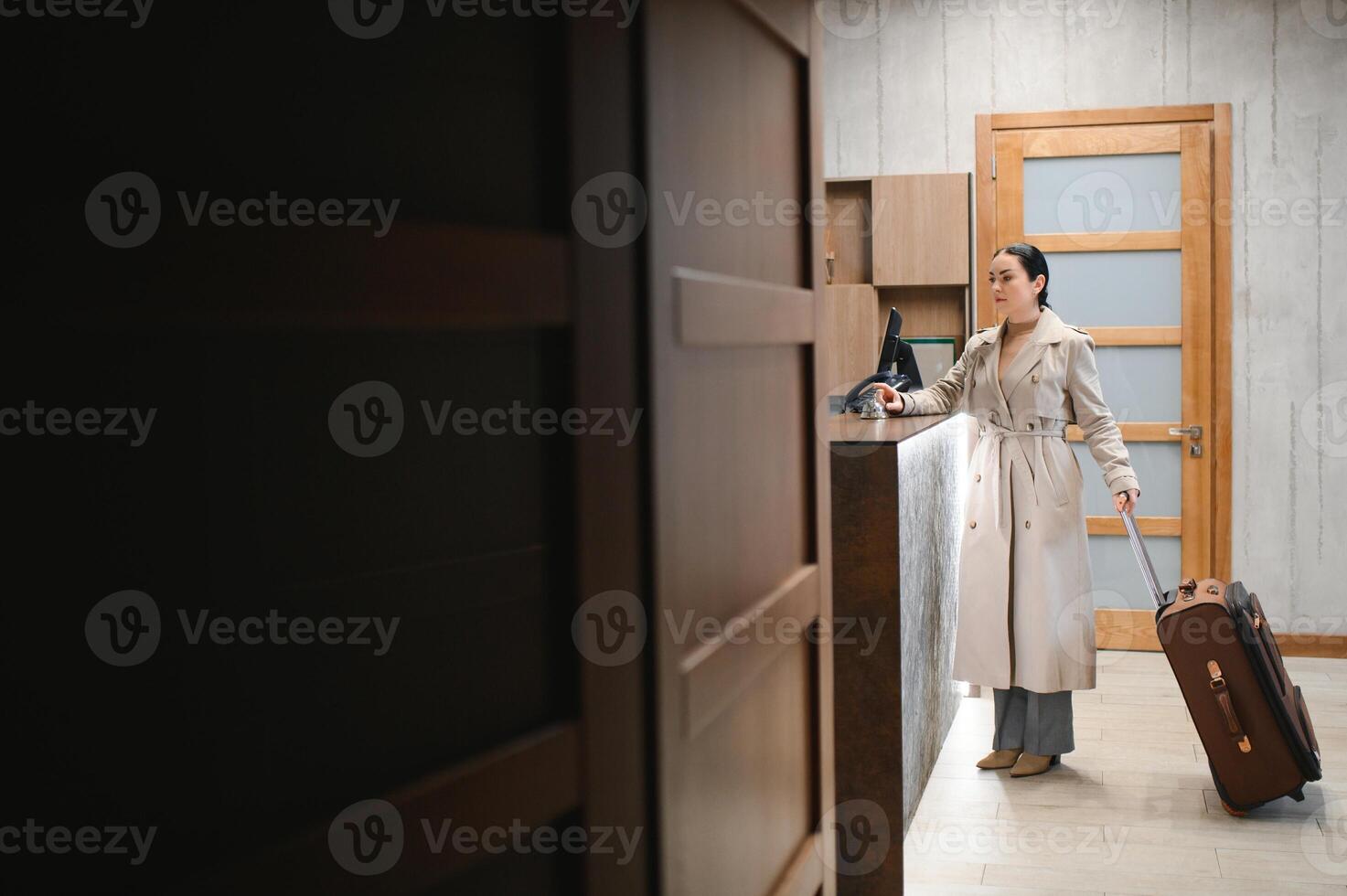 Stylish business woman with suitcase in lobby of luxury hotel. Business travel and pet friendly hotels concept photo