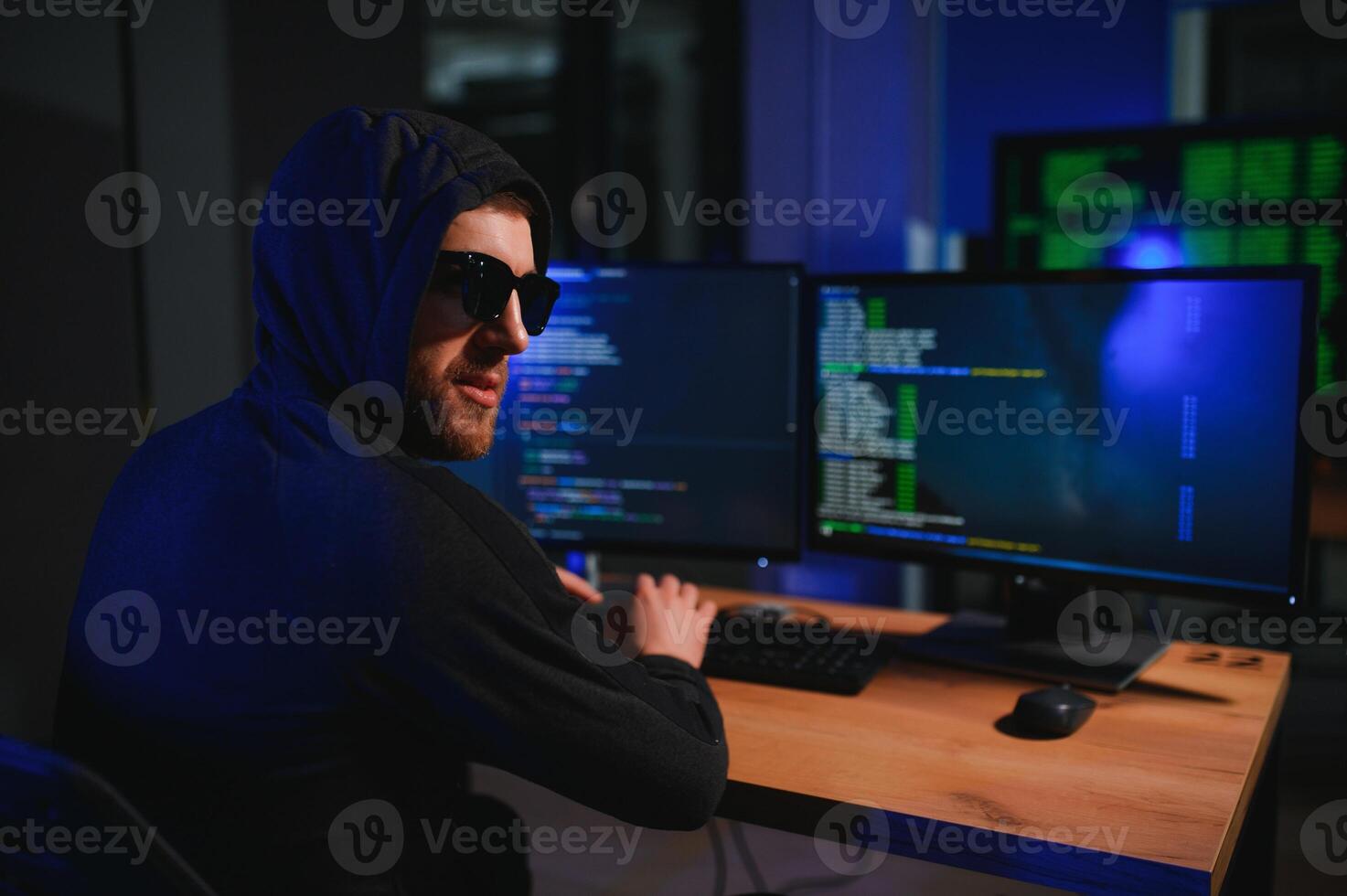 hacker sitting at desk in dark atmosphere. A computer programmer or hacker. Anonymous computer hacker. photo