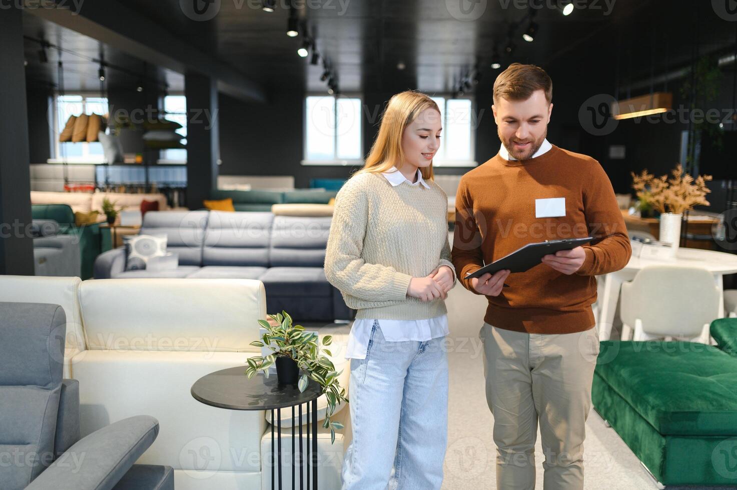 Salesman explaining to woman customer at furniture store photo