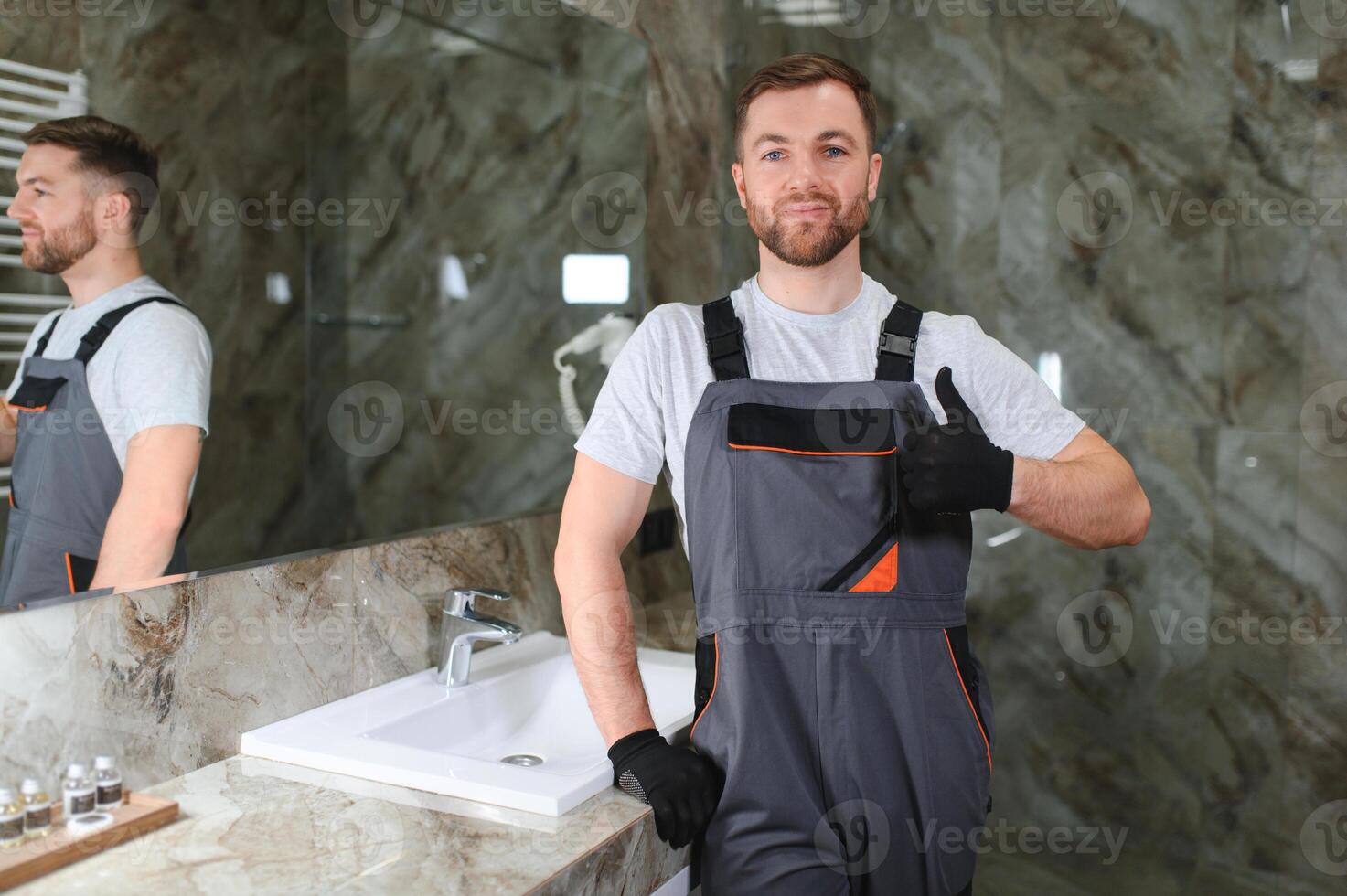 Handsome plumber working in restroom photo