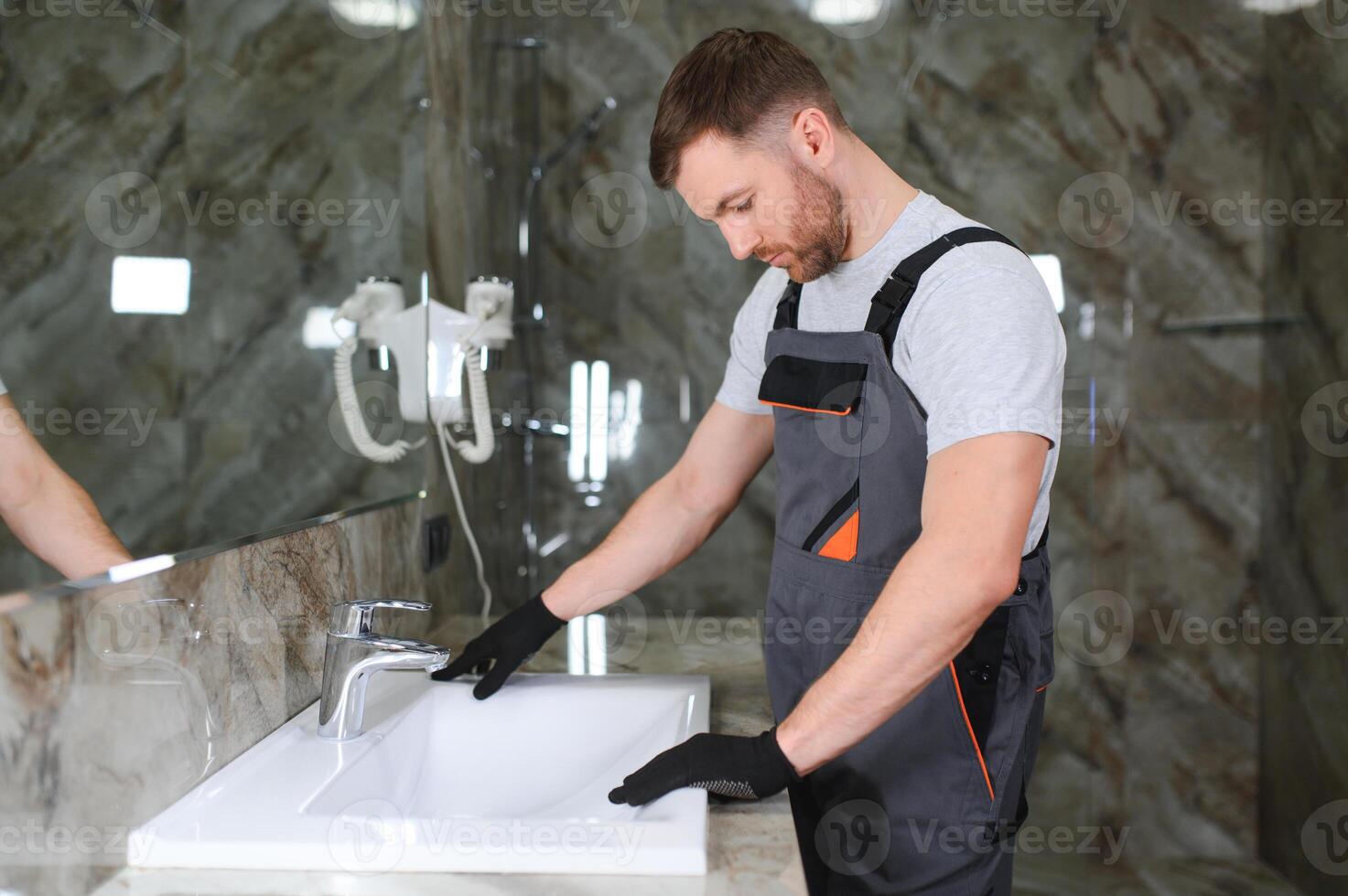 A man is setting the washbasin over the cabinet in the bathroom photo