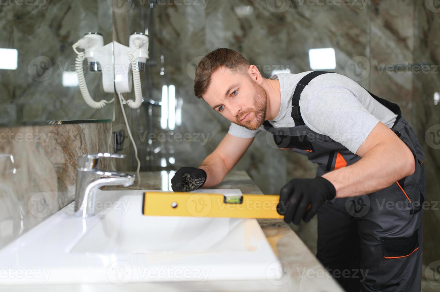 Plumber install sink in bathroom, checks even level of installation. Concept repair service plumbing photo