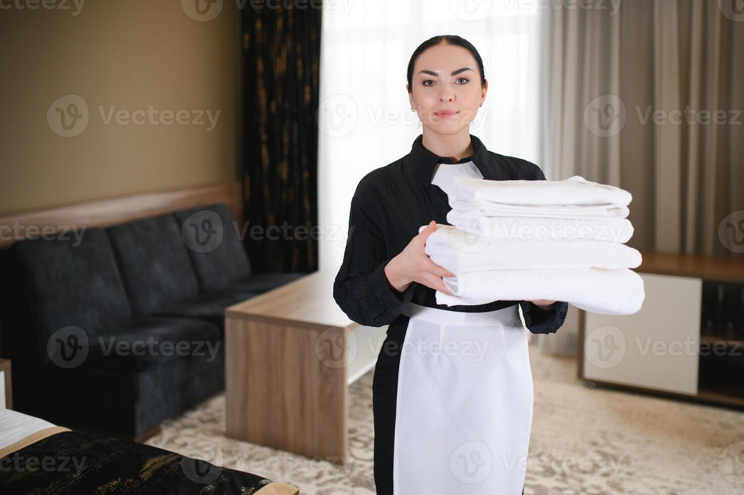 Female chambermaid holding clean white folded towels photo