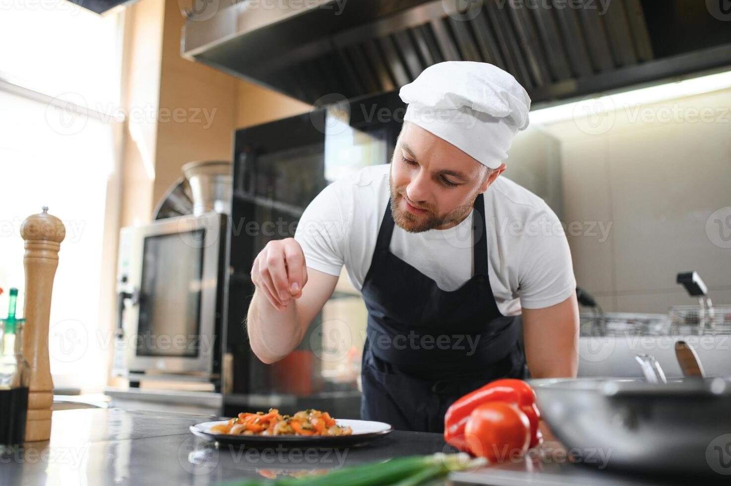 Chef salt slice vegetables and meat. Concentrated chef prepare food. Professional male cook healthy food at commercial restaurant photo