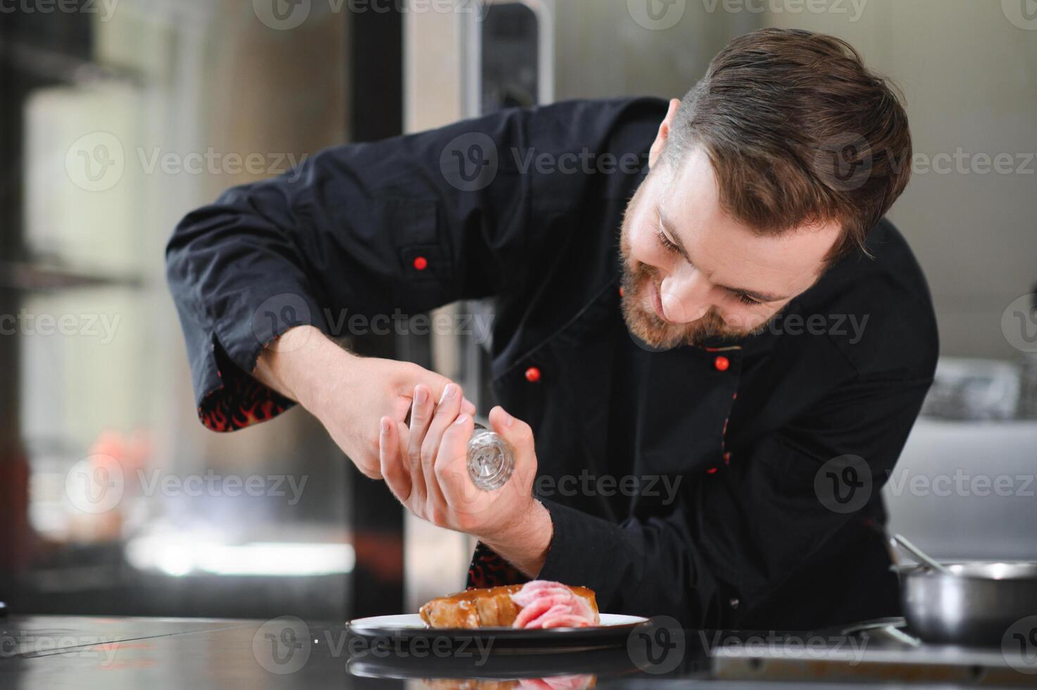 Chef in hotel or restaurant kitchen cooking, he is cutting meat or steak photo