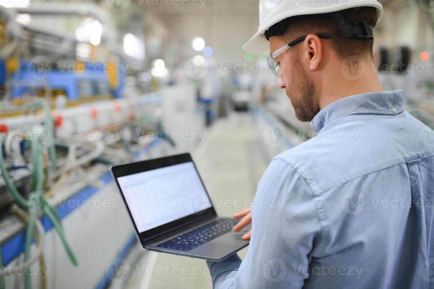 Side view of technician or engineer with headset and laptop standing in industrial factory photo