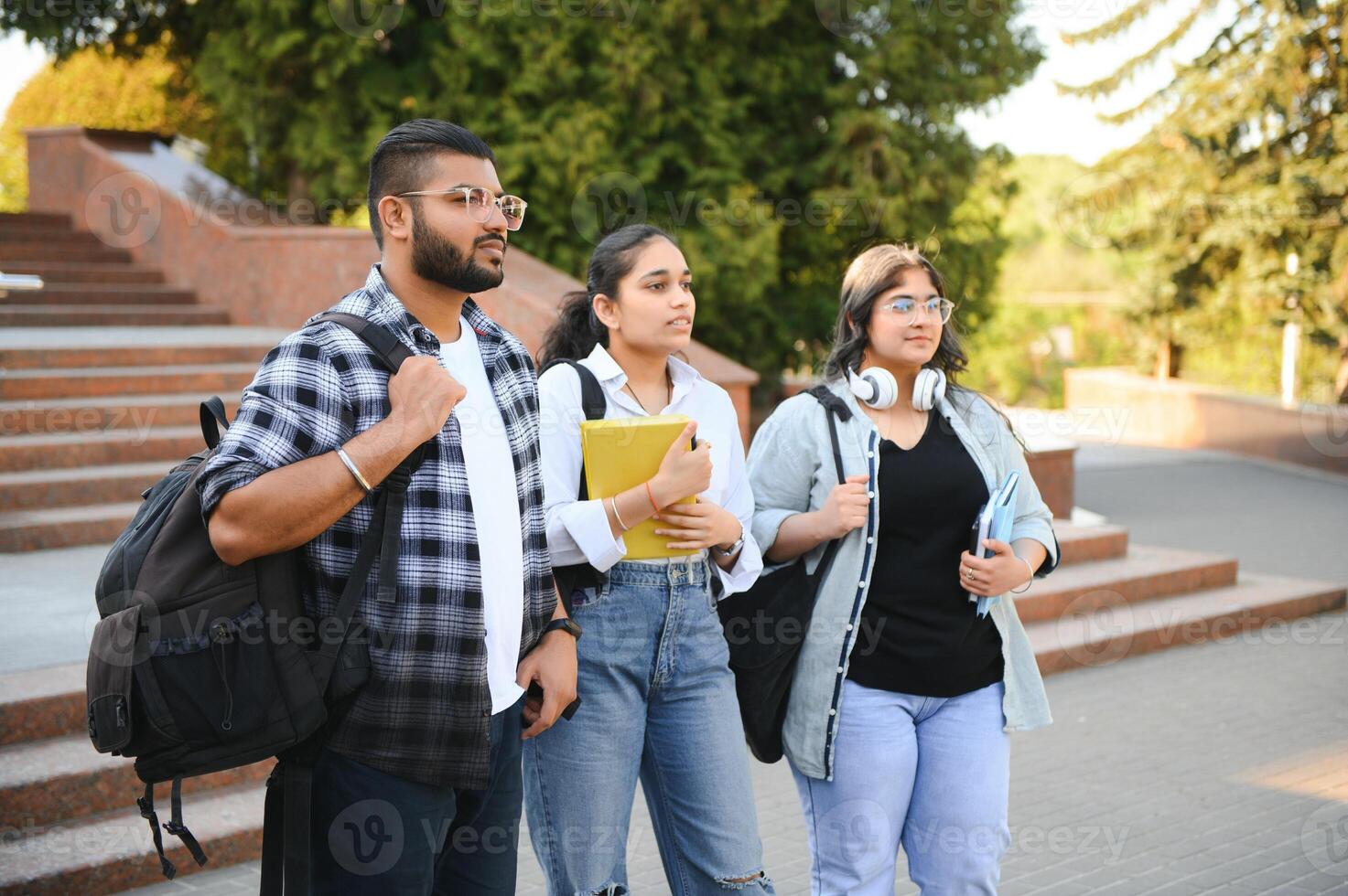 Portrait of three multi-ethnic university students embracing together standing in the campus photo