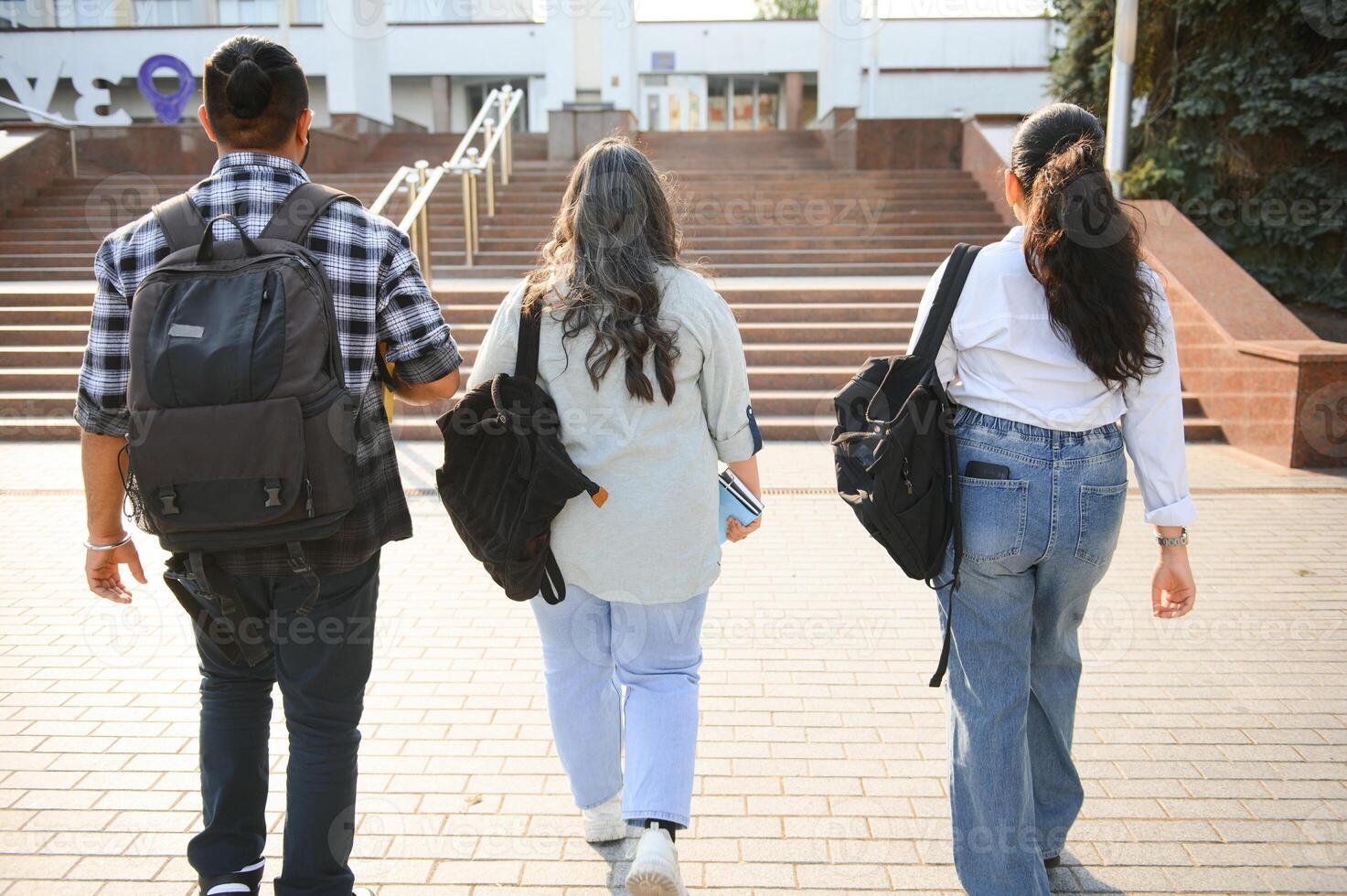 Three international students standing and holding a books photo