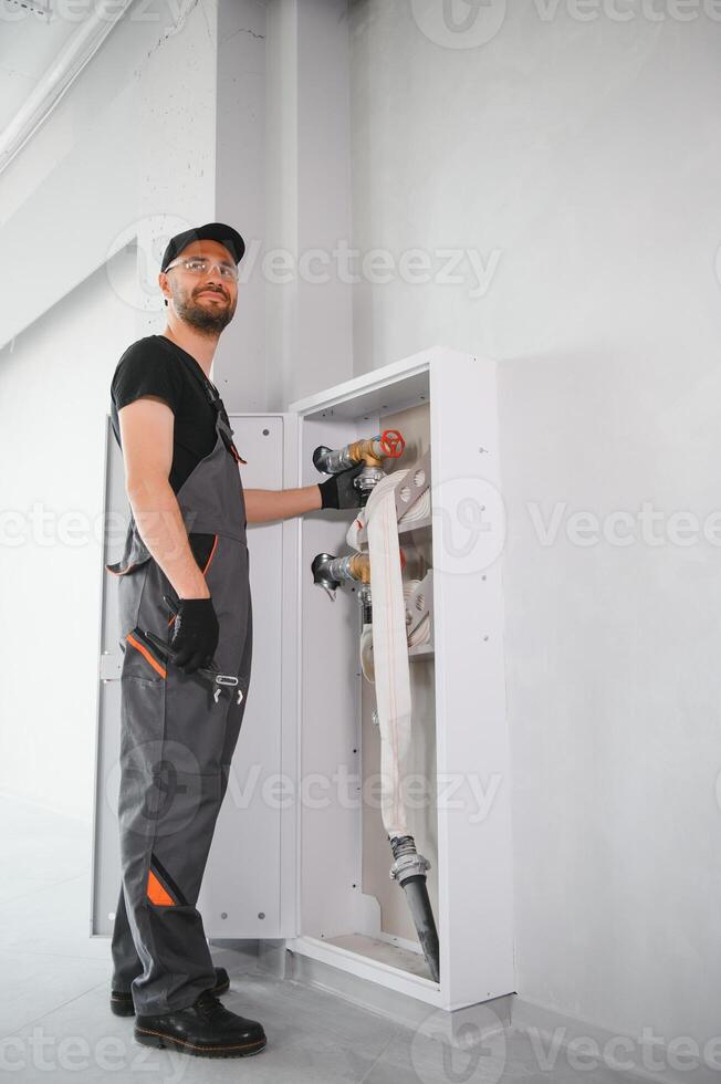 The worker installs or inspects Fire extinguisher and fire hose reel in building corridor photo