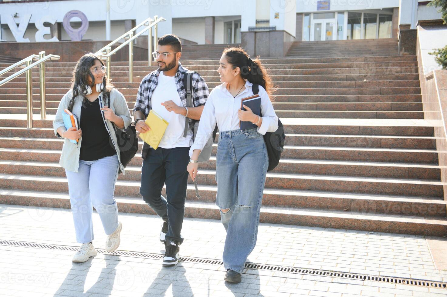 Portrait of three multi-ethnic university students embracing together standing in the campus photo