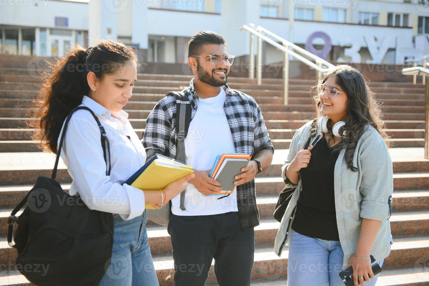 Three international students standing and holding a books photo