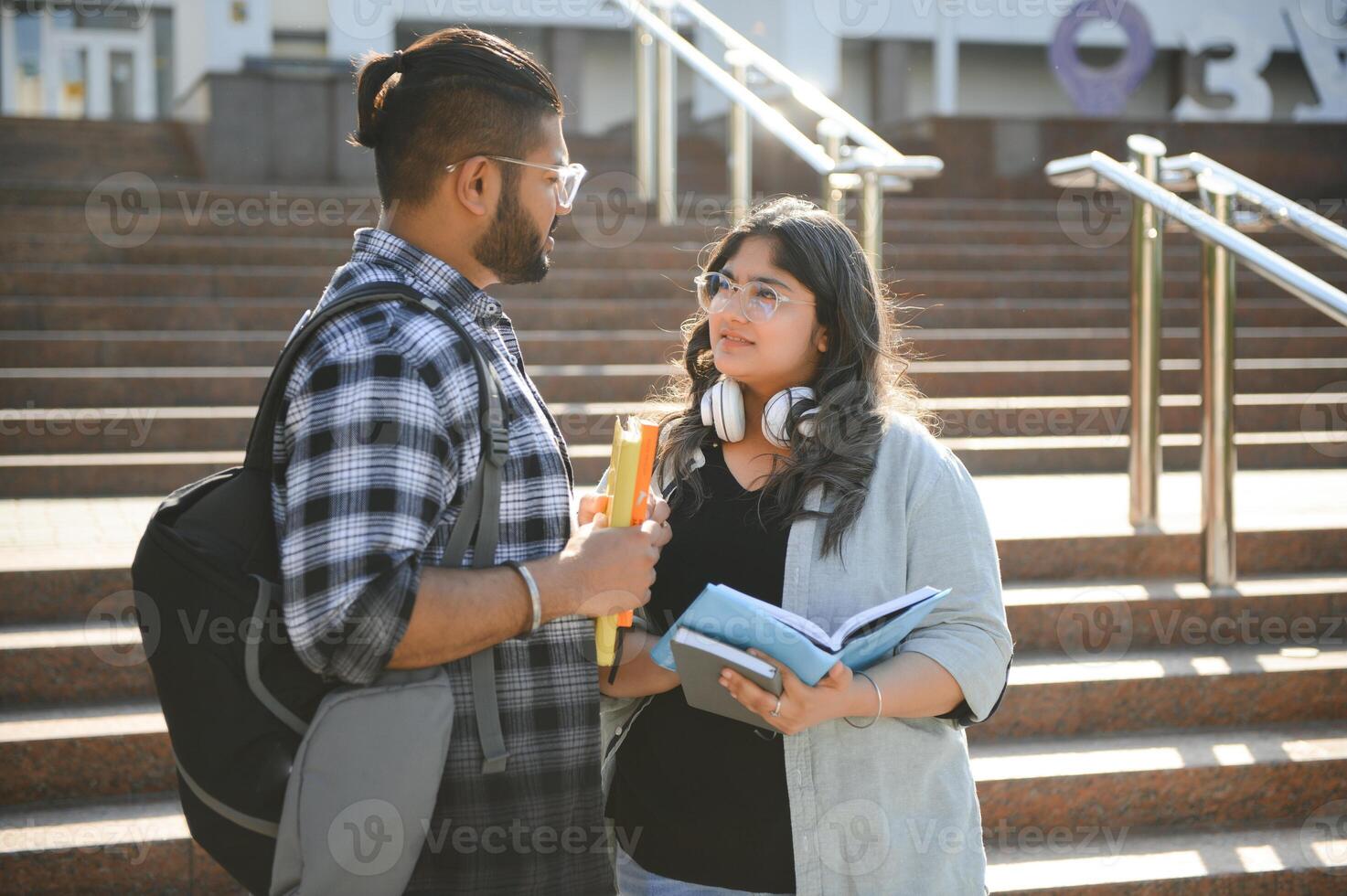 Three international students standing and holding a books photo