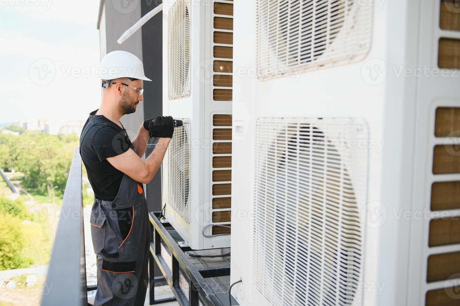 Young man repairman checking an outside air conditioner unit photo