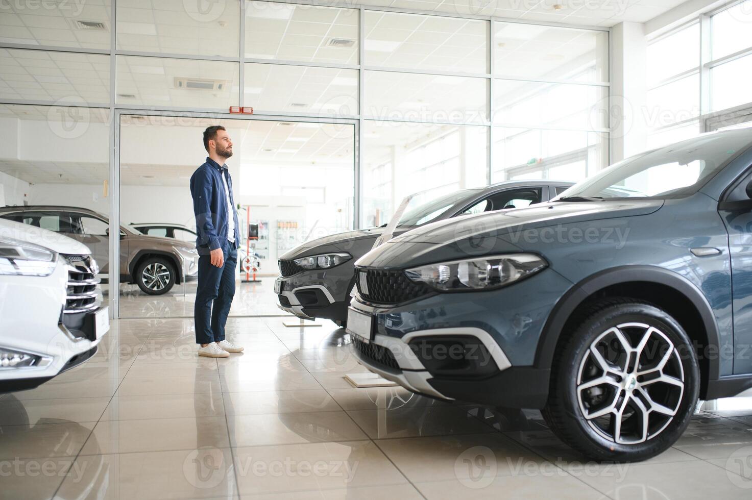 Young man is choosing a new vehicle in car dealership photo