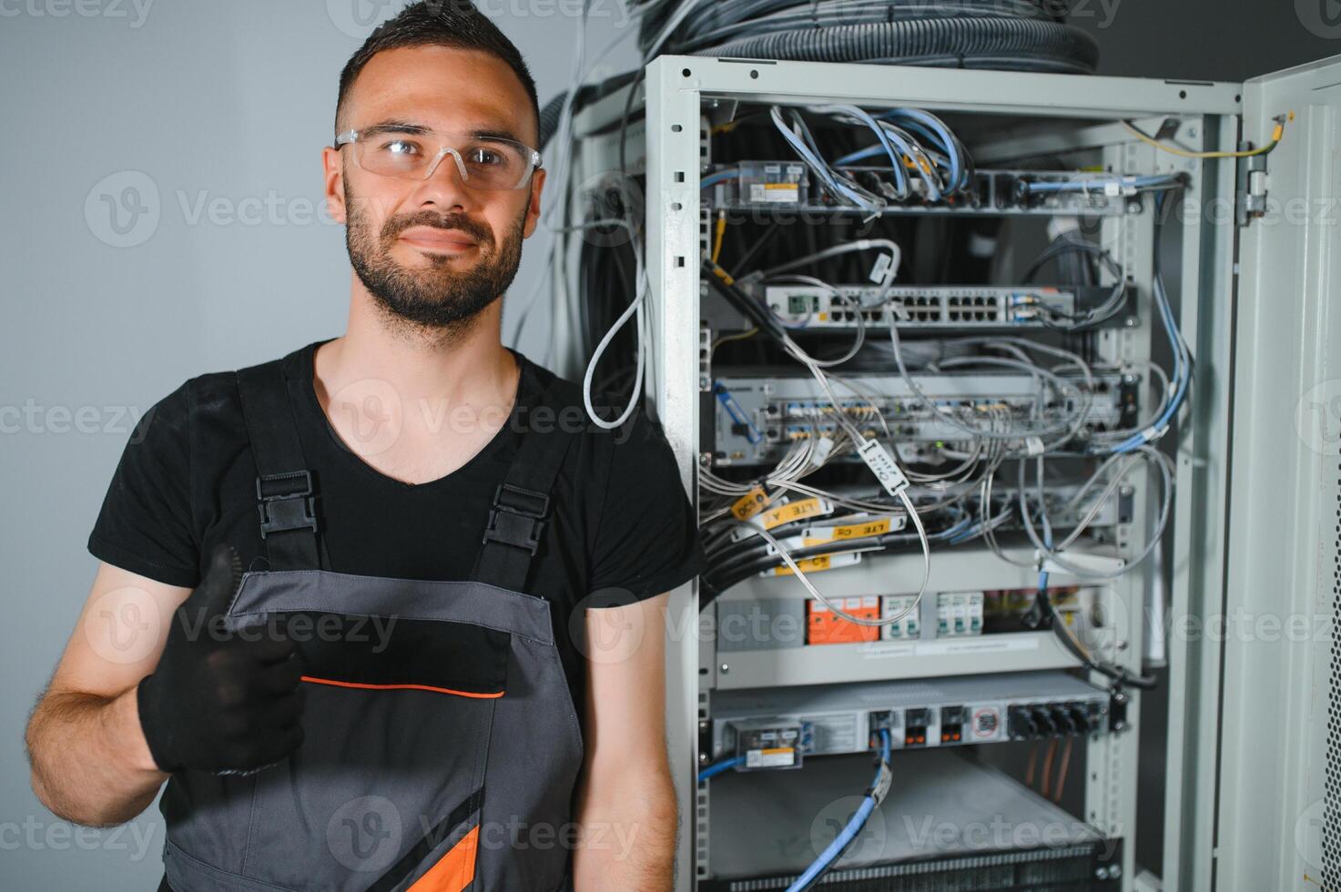A technician works with server equipment in a data center. A man commutes wires in a server room photo