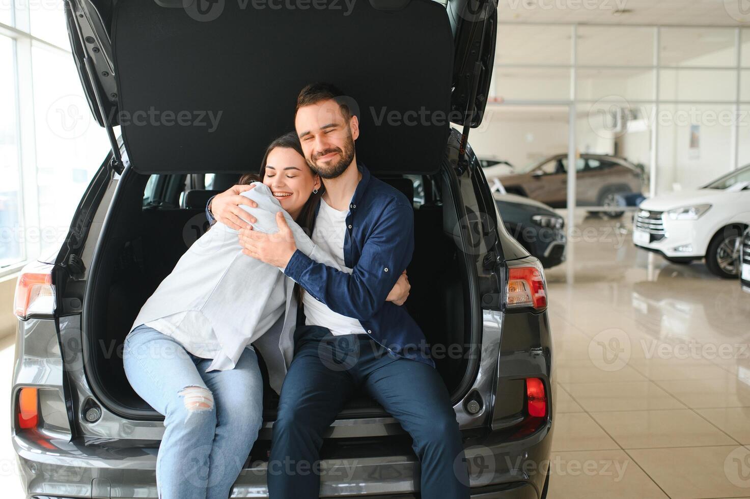 Happy young couple chooses and buying a new car for the family. Visitting the dealership photo