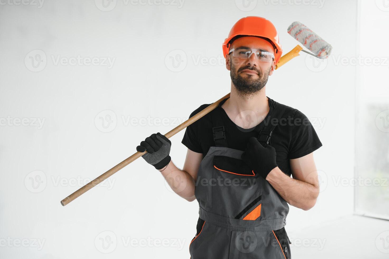 Young cheerful professional painter with paint roller in hands. Repair concept photo